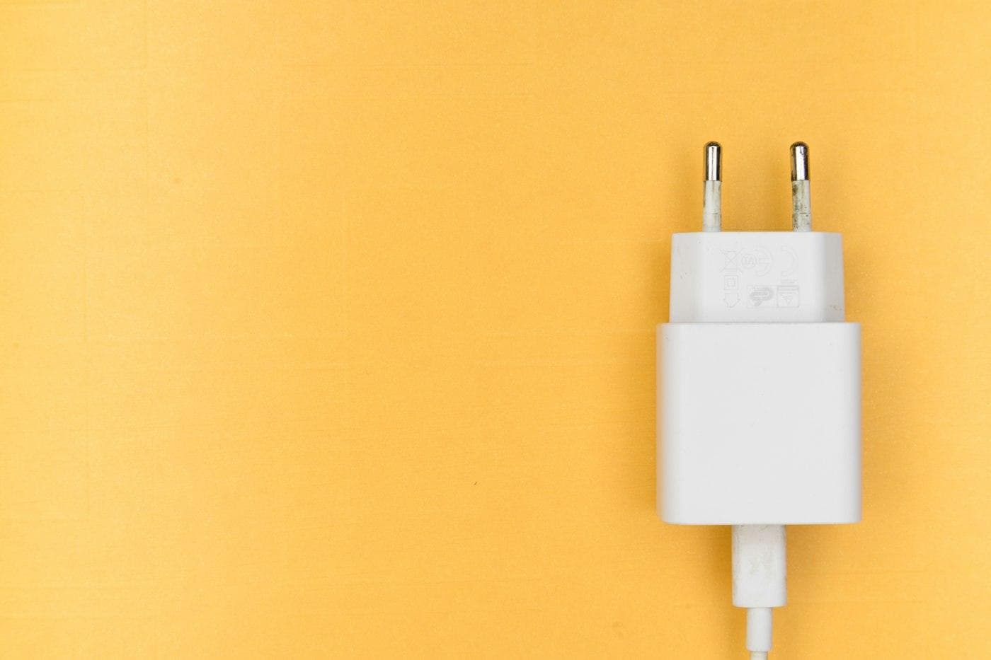 Chargeur secteur blanc et son câble sur fond jaune